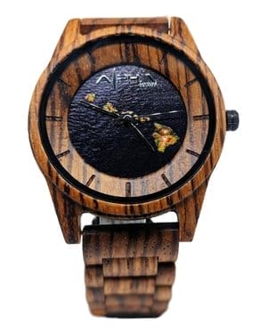 The "Island Time" wooden wristwatch boasts a dark brown face adorned with small gold islands that evoke the beauty of Alpha Maui. It features a minimalist design without numerical hour markers, while the "APEX" brand name is prominently displayed at the top center. Ideal for beachwear, its wooden band completes the stylish look.