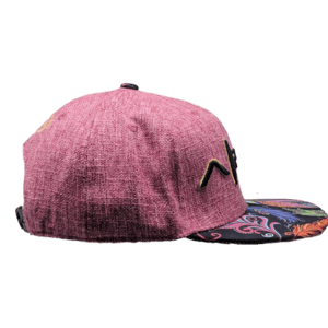 A side view of the "Feathers" cap showcases its pink textured flat-brim design with a striking black and multicolored floral pattern on the brim. Ideal for beachwear, this cap features an eye-catching embroidered yellow and black design on the front panel, adding a touch of Hawaiian flair.