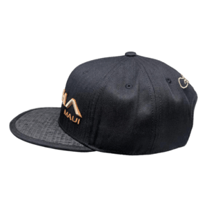 Introducing the Charley Young - (Sunset): A sleek black baseball cap with a flat brim, featuring "Maui" embroidered in gold on the front, accompanied by a wave design above it. Perfect for beachwear, this Alpha Maui hat has a textured pattern on the underside of the brim and an emblem embroidered on the side, capturing that Ohana spirit perfectly.