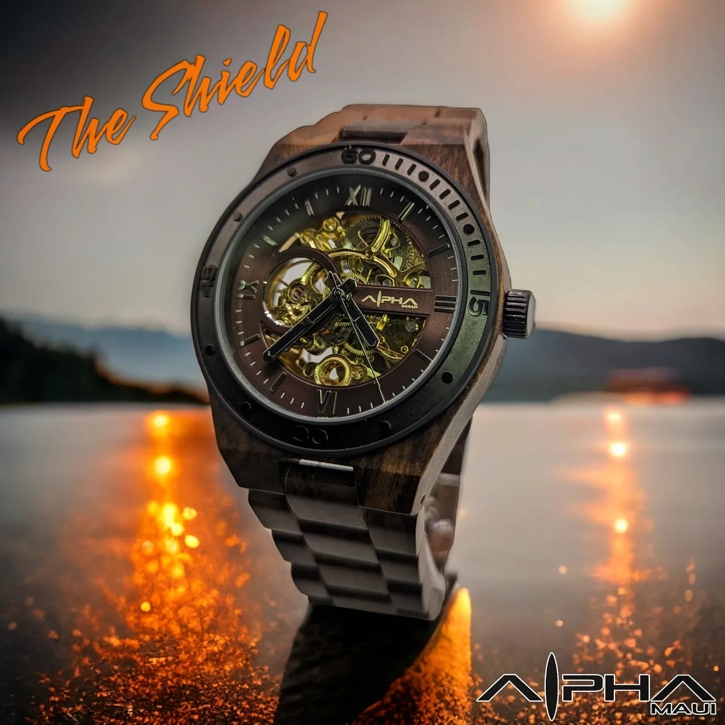 A stylish watch named "The Shield" by Alpha Maui is prominently displayed. The watch features an intricate, exposed gear design at its center. Fiery, golden reflections on the polished surface beneath it intensify its allure, with a serene mountain landscape in the background. Perfect for pairing with your beach apparel.