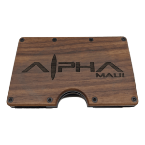 The Alpha Clip is a rectangular wooden cutting board with rounded edges and metal screws at the corners, featuring the engraved text "Alpha Maui" with a stylized surfboard or fin design incorporated into the letter "A" in "Alpha." It's perfect for adding a touch of Ohana spirit to your kitchen, inspired by Hawaii.