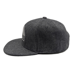 A side view of The Specialist baseball cap with a flat brim in dark gray. It boasts a subtle texture and a geometric logo on the front panel. Ideal for your beach apparel collection, its minimalist design exudes an effortlessly cool vibe that says Aloha.