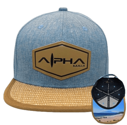 Presenting the "Kam 2": A light blue and tan baseball cap featuring a hexagonal patch that reads "Alpha Maui Ohana." The brim showcases a woven tan pattern, while the underside reveals a beach scene with palm trees and the beautiful ocean of Hawaii.