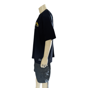 A mannequin is dressed in "The Vibes" black T-shirt featuring a vibrant geometric design on the front, paired with dark gray cargo shorts—an ideal ensemble for beachwear. Positioned in a side view facing left, the mannequin's bald and featureless head enhances its sleek appearance.