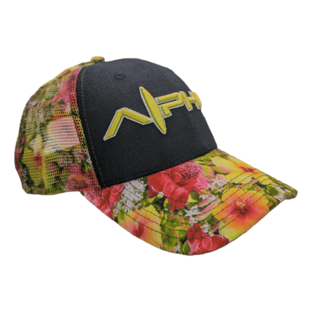The Alpha Maui Botanical Queen is a colorful floral-patterned baseball cap featuring green, yellow, and red hues inspired by Hawaii. The front panel and bill are adorned with vibrant flowers, while the rest of the cap has a black mesh design. The logo on the front panel displays "NAH" in bold yellow letters.