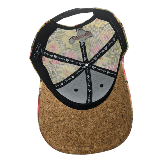 A cork cap is shown from underneath, highlighting its interior structure. The inside features a black band with repeated white text, a mesh top, and a grey inner lining. A heart symbol is visible on one side, and a partially visible tag reading "Alpha Maui Botanical Queen" hints at its beach apparel origins.
