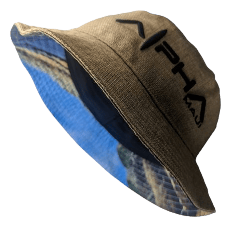 Introducing the "Alpha Maui Bucks Hemped Out," a light brown bucket hat displaying the text "Alpha Maui" in bold black on the front. Ideal for adding to your beach apparel collection, this hat features a vibrant tropical scene—with a coastline, blue sky, and lush greenery—on the inner brim.