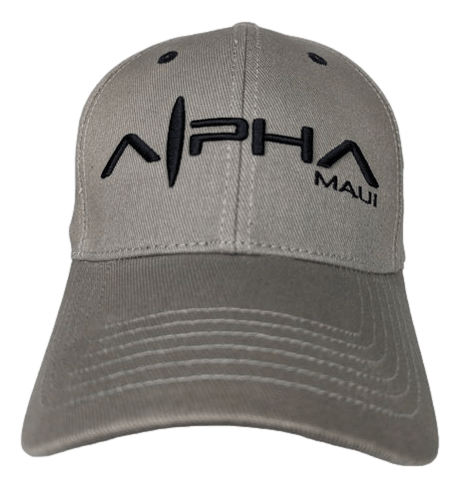 A beige Tinsman Flex baseball cap with black embroidered text on the front, reading "Alpha Maui." The "A" in "Alpha" is cleverly stylized to resemble an Alpha symbol (α). Perfect for showing your Ohana spirit, the cap features a curved brim and visible stitching details.