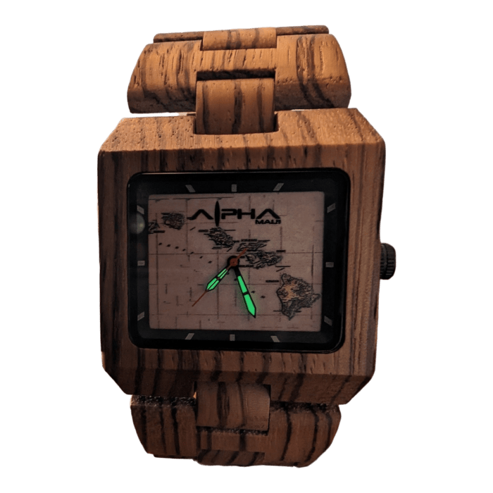 Introducing the Island Time: a wooden wristwatch featuring a square face with a matching wooden band. The watch face showcases a map of Hawaii, while the hands glow in the dark—the hour hand in green and the minute hand in red. The brand name, "Alpha Maui," is prominently printed at the top of the watch face.