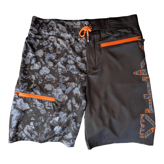 The Lava Flow board shorts boast a unique split design. The left side showcases a striking black and white rock pattern with an orange zipper pocket, while the right side is solid black adorned with "Alpha Maui" in bold orange letters. An orange drawstring at the waist completes these perfect shorts for your Hawaii adventures.