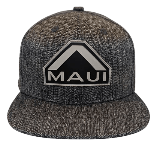 The Specialist is a gray snapback hat featuring a black and white emblem on the front, displaying the text "Maui" beneath an abstract mountain design. The fabric boasts a subtle herringbone pattern, making it perfect for repping Alpha Maui.