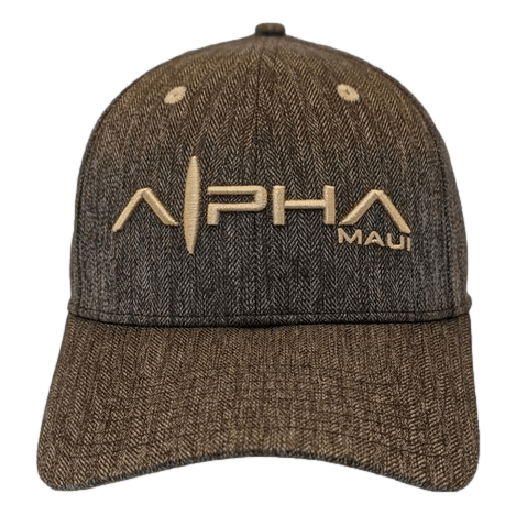 Introducing the Alpha Maui CocoNuts II: a brown baseball cap with textured fabric, featuring embroidered "Alpha Maui" text in beige letters on the front. Perfect for beach apparel, this cap boasts a curved brim and two small ventilation holes on the front panels, radiating Aloha vibes all around!