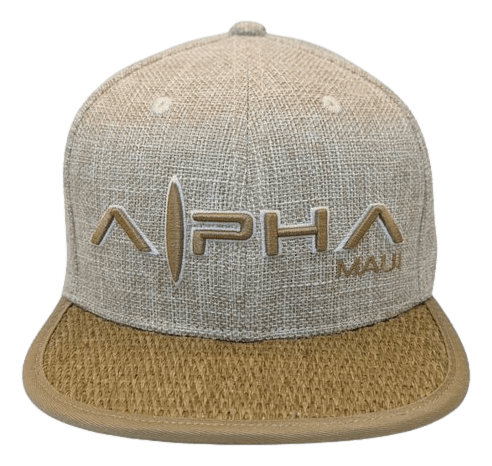 The Wailea Grand cap is a beige textured hat featuring "Alpha Maui" prominently embroidered in large letters on the front, with "Ohana" in smaller letters beneath it. The cap also boasts a curved brim with a distinct woven-like texture that perfectly captures the spirit of Hawaii.