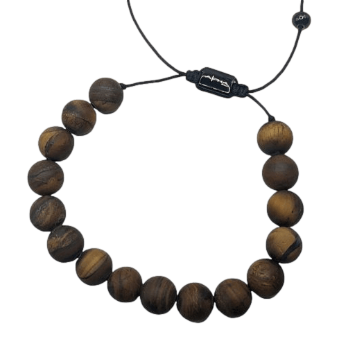 The Alpha Maui Band - Zebrawood 42mm (42-49mm) features round wooden beads strung on a black cord, showcasing the natural wood grain pattern reflective of Hawaii's tropical forests. This bracelet is equipped with an adjustable sliding knot closure and includes a small black charm with an engraved design near the knot, embodying the spirit of Aloha.