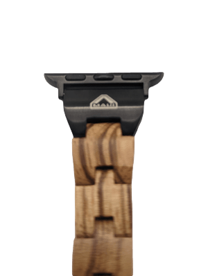 A close-up view of the Alpha Maui Band - Zebrawood 42mm (42-49mm) reveals a watch strap crafted from light brown zebrawood with a segmented pattern. The strap, evocative of beachwear, is fastened with a black metal clasp that bears the brand's logo. The elegant design resonates with a touch of Ohana and Aloha. The background is white.