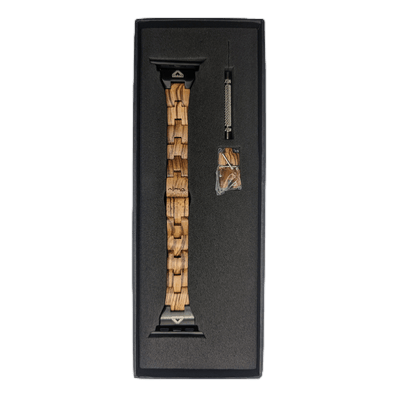 The Alpha Maui Band - Zebrawood 42mm (42-49mm) with black connectors is neatly displayed in a black case. Next to the watchband, a small metal adjustment tool and additional links in a plastic bag are placed. The watchband, perfect for beach apparel, boasts a unique, segmented pattern featuring different shades of wood. Aloha!