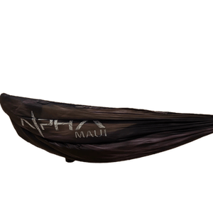 A black hammock called "The Sky Sleeper" prominently displays the text "Alpha Maui" alongside a logo that features a stylized wave and a star. The hammock is fully stretched out, clearly showcasing the text and design, with no background elements included so that only the hammock is in view.