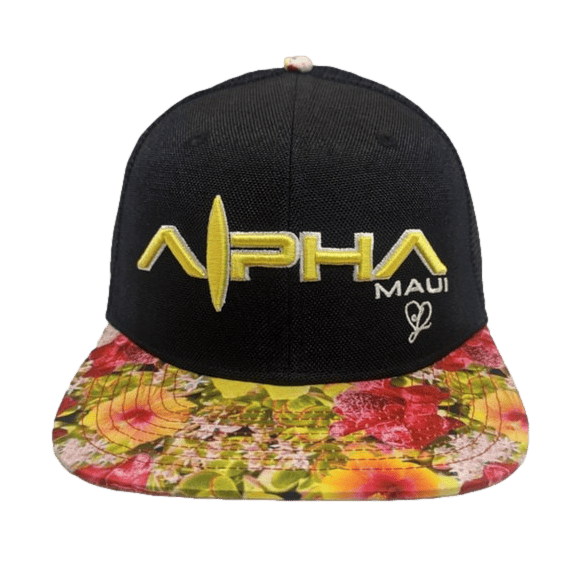 The "Alpha Maui Botanical Queen" is a black baseball cap featuring "Alpha Maui" embroidered on the front in large yellow letters accented by smaller white lettering. Its flat brim boasts a vibrant floral pattern, while a small white heart design on the right side captures the essence of Aloha.