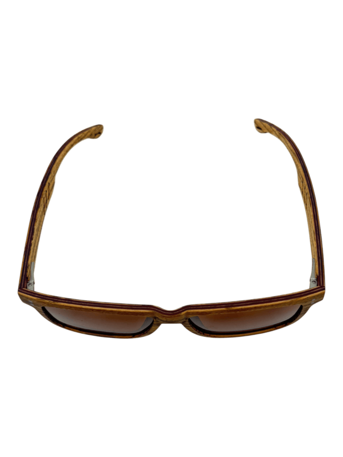 The Cruisers 2.0 sunglasses feature dark lenses and a distinct wooden frame with natural grain, elegantly showcased from above against a black background.