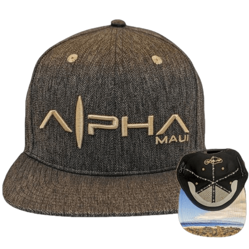 A CocoNutz grey baseball cap with a chevron pattern and the text "Alpha Maui" embroidered in gold on the front. This piece of beach apparel also showcases the underside of the cap's brim, which features a photograph of a coastal landscape, embodying the spirit of Aloha.