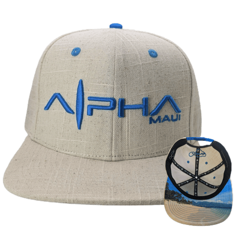Introducing "Beachy": A beige baseball cap adorned with blue embroidery reading "Alpha Maui" on the front. Below the cap, a smaller image displays the underside of the brim, showcasing a printed scene of a sandy beach with palm trees and a clear sky, perfectly capturing that Aloha spirit of Hawaii.