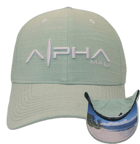 The Sprecklesville baseball cap is light green with "Alpha" embroidered in white on the front. Below "Alpha," the word "Maui" is stitched in smaller white text. The underside of the brim features a scenic beach and ocean view, making it perfect for your beach apparel collection.