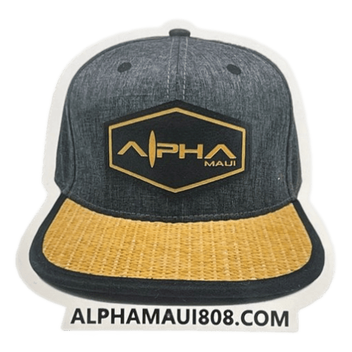 Image of a baseball cap with a grey crown and a tan brim. The front features a black and gold hexagonal patch reading "Let The Universe...Do It's Thing," radiating Aloha spirit. Below the cap, the website "alphamaui.com" is printed, inviting you to join the Ohana.