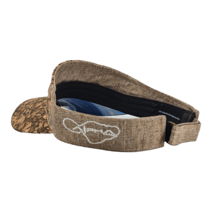 The Alpha Maui Mauka features a cork-textured visor and a brown strap, with a white embroidered design on the back that resembles the geographical outline of Hawaii. Perfect for beach apparel, the inner side is black with some text visible along the strap.