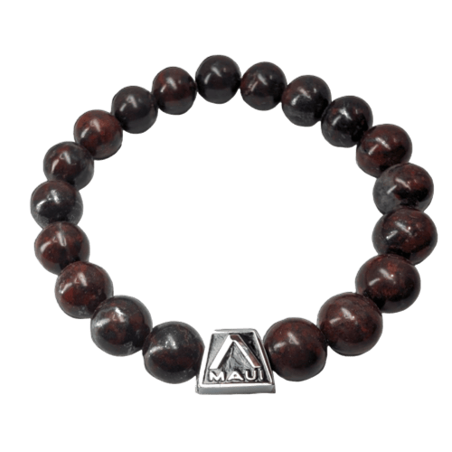 The Alpha Maui Sapphirelet is a round beaded bracelet made of dark, polished stones connected by an elastic thread, perfect for beach apparel. It features a metallic triangular charm engraved with the word "Maui," evoking the spirit of Hawaii.