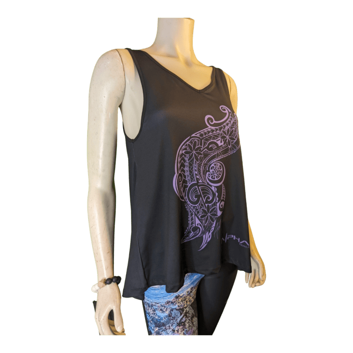 A mannequin wearing the Alpha Maui U'i Tank, which is a sleeveless black top featuring a purple abstract design on the front. The top showcases a flowy, asymmetrical hem that evokes Alpha Maui’s beach apparel style. The mannequin is also dressed in patterned leggings and accessorized with a black bracelet on its left wrist.