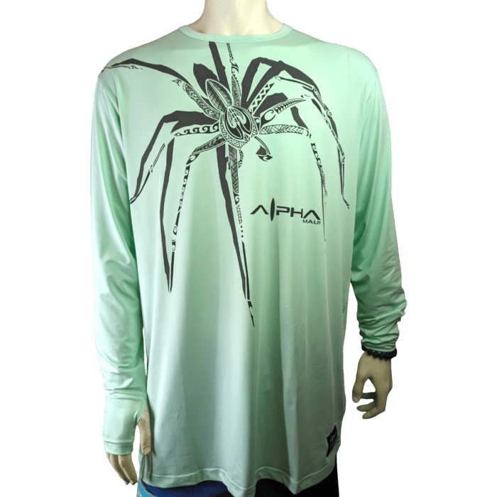 A mannequin is showcasing the Alpha Maui U'i Tank, a light green long-sleeve shirt adorned with an abstract black spider design on the chest and featuring the "Alpha Maui" logo in black. The shirt is ideal for beach apparel enthusiasts. The mannequin's left arm is slightly bent, set against a plain white background.