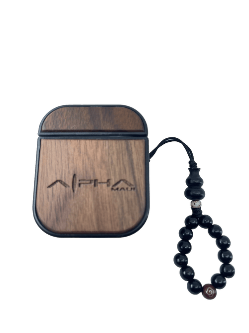 An Alpha Airpod Case made from wood, featuring the engraved text "Alpha Male," accompanied by a dark beaded bracelet strung together. The case boasts a smooth finish and sleek, compact design perfect for your beach apparel. The bracelet showcases spherical black beads accented with a single bead adorned with a red and white spiral design.