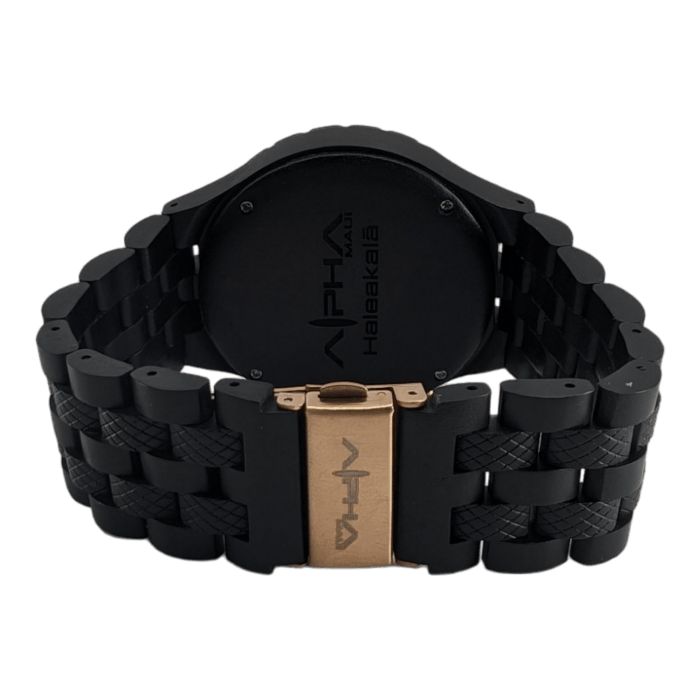 The Alpha Maui The Haleakalā wristwatch features a black design with a metallic band and clasp. The back plate of the watch is imprinted with the brand name "Alpha HALEAKALĀ," and the same brand name and logo are present on the clasp. This watch embodies a modern, rugged design inspired by Alpha Maui's adventurous spirit.