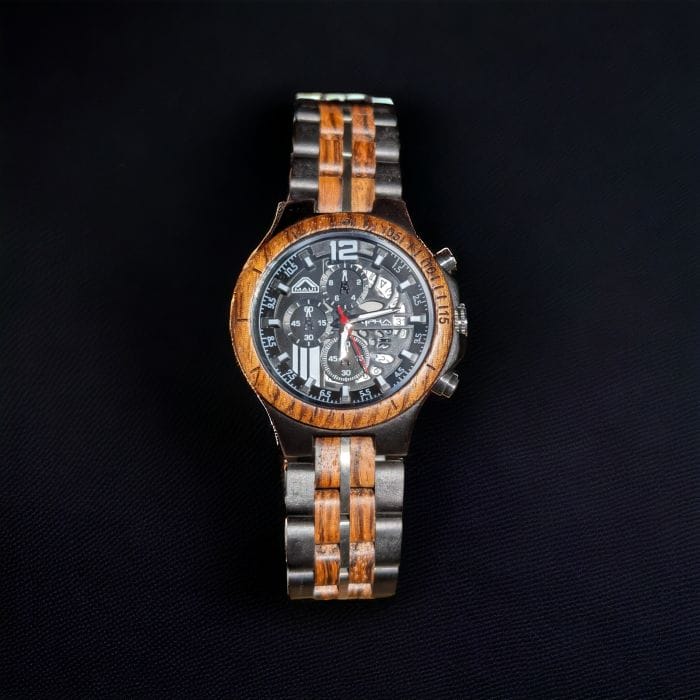 A stylish wristwatch with a brown and silver metallic band, known as the Aloha Alpha Maui, is displayed against a black background. The watch features a detailed black dial with white numerals, multiple small dials, and intricate designs. The bezel has engraved markings.