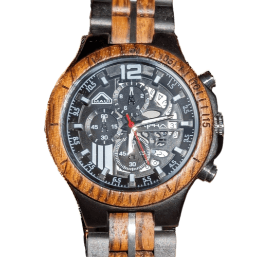 A close-up of an Alpha Maui wristwatch with a mixed wooden and metal strap. The watch face is black with intricate subdials, silver hour markers, and large numbers at the 12 and 6 positions. The watch has three metallic buttons on the side and proudly features the brand "Maui.