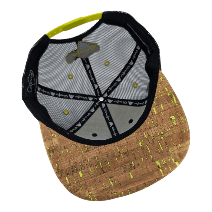 Check out the inside view of the Alpha Maui The Valley Isle cap, showcasing a cork-textured brim with yellow speckles. This stylish cap's interior is mesh-designed for optimal breathability and features a pattern of lines and inscriptions along the seams. The color palette includes black, white, yellow, and cork brown—perfectly embodying the Alpha Maui vibe that's ideal for beach apparel.