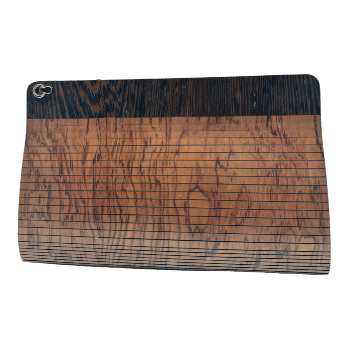 Introducing the Alpha Maui The Clutch Carrier, a cutting board with a rich dark wood grain pattern and horizontal lining evocative of Hawaii’s lush landscapes. This distinctive piece features a small hole in the top left corner for convenient hanging. Its subtle curve adds an elegant touch, imbuing your kitchen with the warm Aloha spirit.