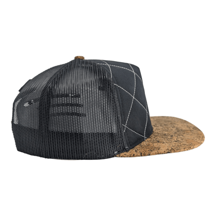 A black mesh trucker hat with a structured crown featuring a diamond pattern stitched design, labeled as Alpha Maui. The brim is made of a cork-like material, giving a textural contrast to the mesh. The hat is set against a plain black background, reminiscent of Hawaii's rugged landscapes and Ohana spirit.