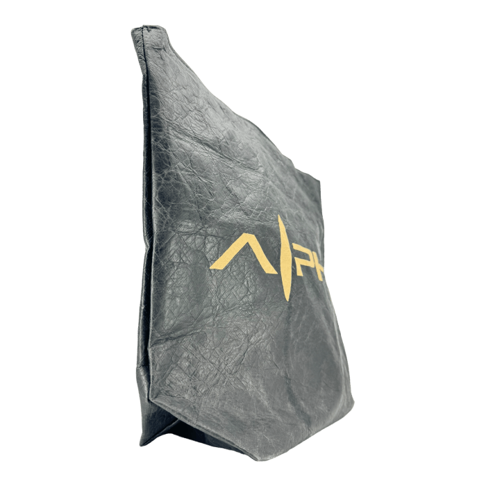 The Alpha Maui Dupont Bag, a black rectangular bag made of paper or fabric with a crinkled texture, showcases the gold "A|PW" logo on one side and stands upright against a plain black background—exuding Aloha elegance and Ohana pride.