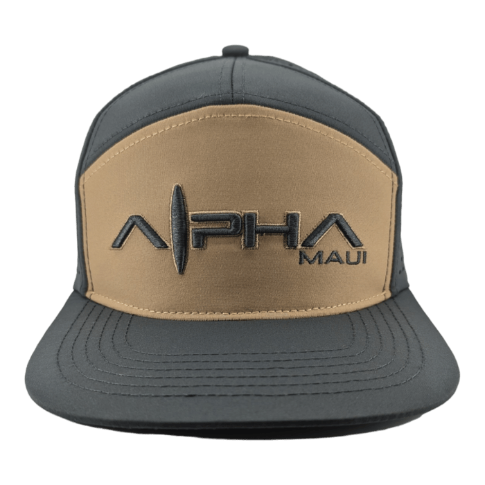 A baseball cap with dark gray panels and a tan front section, featuring the text "Alpha Maui" in black embroidery alongside a surfboard graphic. The cap has a flat brim, perfect for catching those Hawaii vibes, and is shown against a white background.