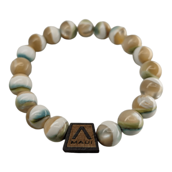 The Shell Pearlet is a beaded bracelet that displays round, marbled beads in hues of white, cream, green, and brown. It features a rectangular wooden charm with the word "Aloha" and a stylized logo etched onto it. The bracelet is arranged in a circular shape against a plain background.