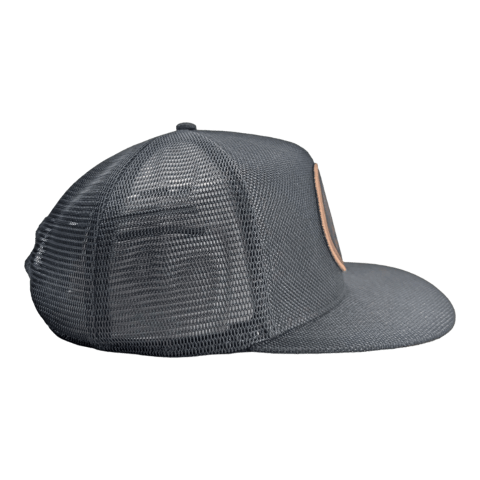 A side view of The Balance dark gray mesh baseball cap with a flat brim. The front panel appears slightly solid, while the back and sides are made of breathable mesh material. The cap rests on a black background.