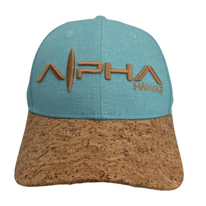 A turquoise baseball cap named "Turtle Cove II" with a beige cork brim. The front of the cap features the embroidered text "ALPHA HAWAII" in tan, with a surfboard design incorporated into the "A" of "ALPHA.