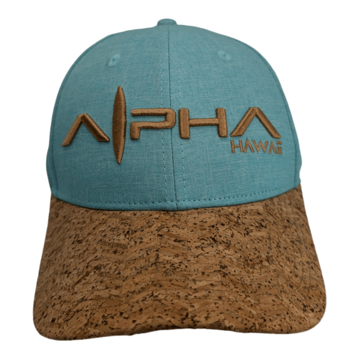 A Turtle Cove II baseball cap in turquoise, featuring a light brown cork brim. The cap is embroidered with the word "ALPHA," with a surfboard incorporated into the first "A," and "HAWAI'I" in smaller letters to the side.