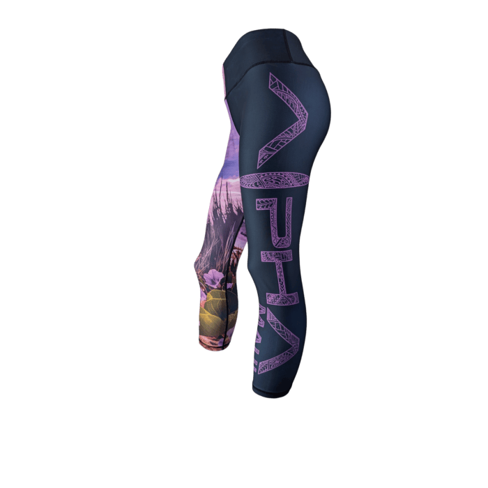 Introducing the Pohuehue leggings: a pair of dark athletic leggings adorned with a vibrant floral pattern on the left leg and bold purple "VHA" letters down the right leg, showcased against a sleek black background.