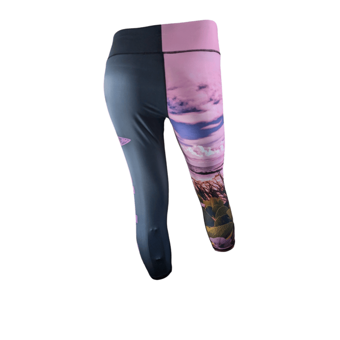 Introducing the Pohuehue women's leggings, which feature a distinctive design: the left leg is solid black, while the right leg showcases a nature-themed print in pink and purple hues with clouds and floral elements. The broad black waistband adds comfort and style. The leggings are displayed from the back.