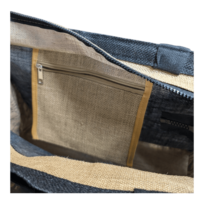 The image showcases the interior of the Tribal Wai bag, featuring a black and beige fabric design. Inside, there is a small zippered pocket stitched into the lining, complete with a beige zipper and tan fabric trim. The spacious interior also reveals visible stitching on the bag's material.